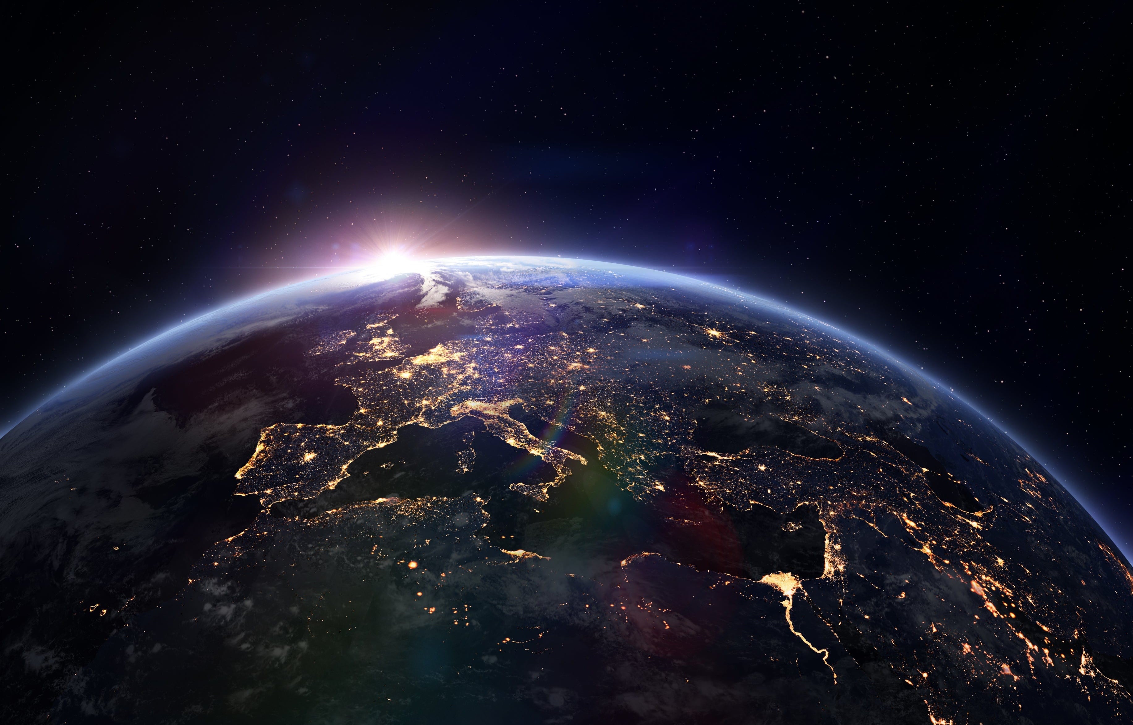 Vibrant Earth from space, nighttime cities of Europe illuminated, brilliant sunrise, thin blue atmosphere, dark starry sky
