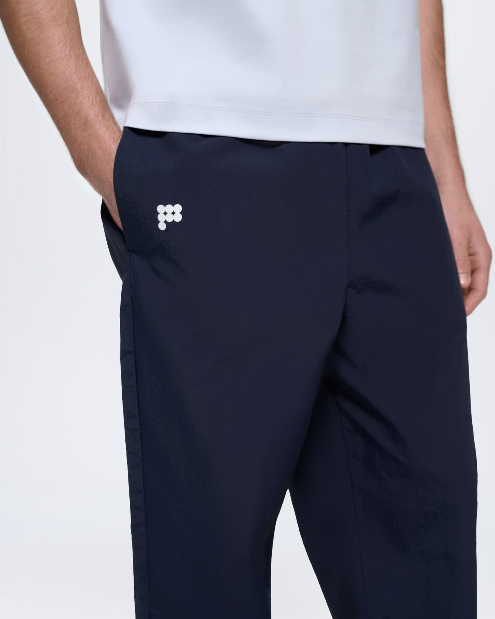 Mens oversized Granite Navy Recycled Nylon Track Pants, 100% recycled polyamide, lightweight, white logo on model