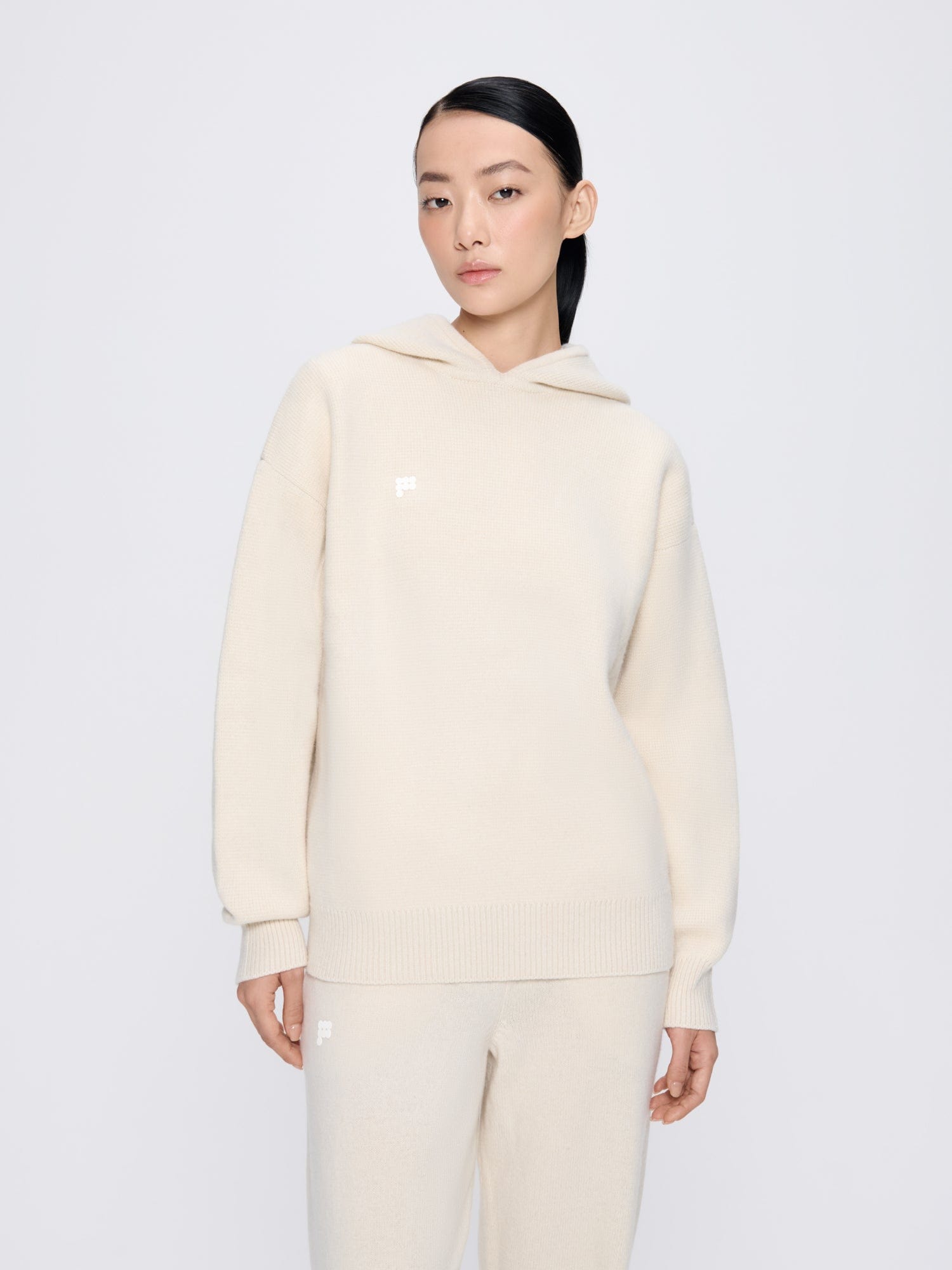 Womens ecru ivory oversized recycled cashmere hoodie. Model in soft knit with ribbed cuffs and matching loungewear pants