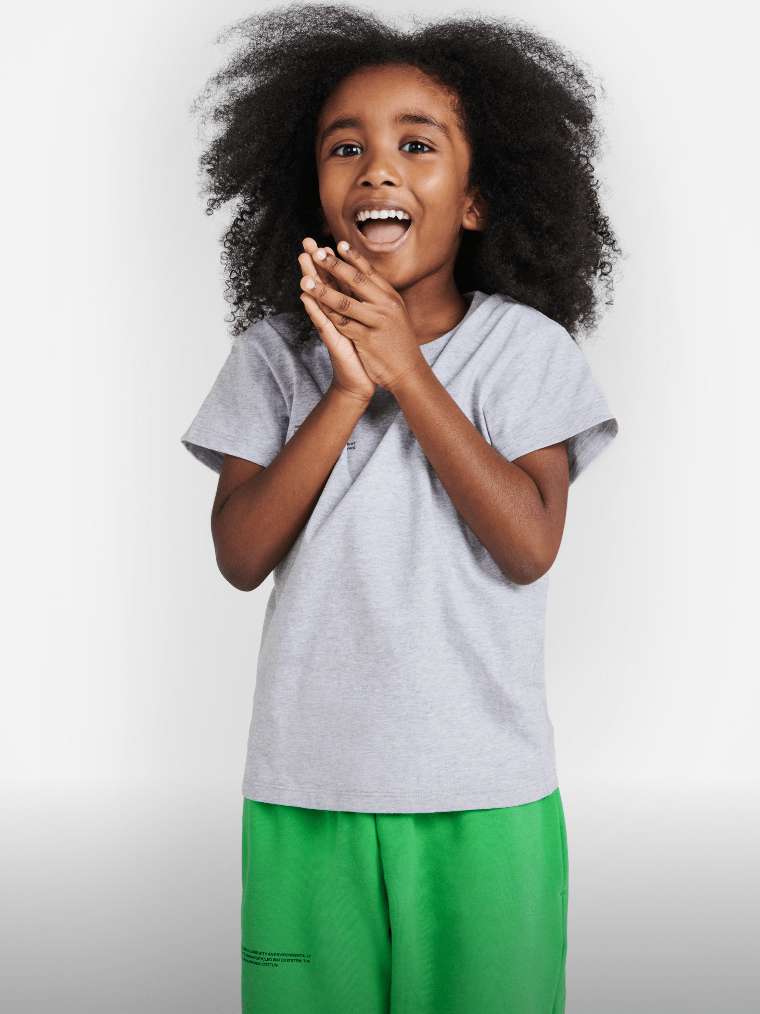 Happy child in grey melange short-sleeve tee with text print, paired with vivid green comfortable sweatshorts Kids fashion