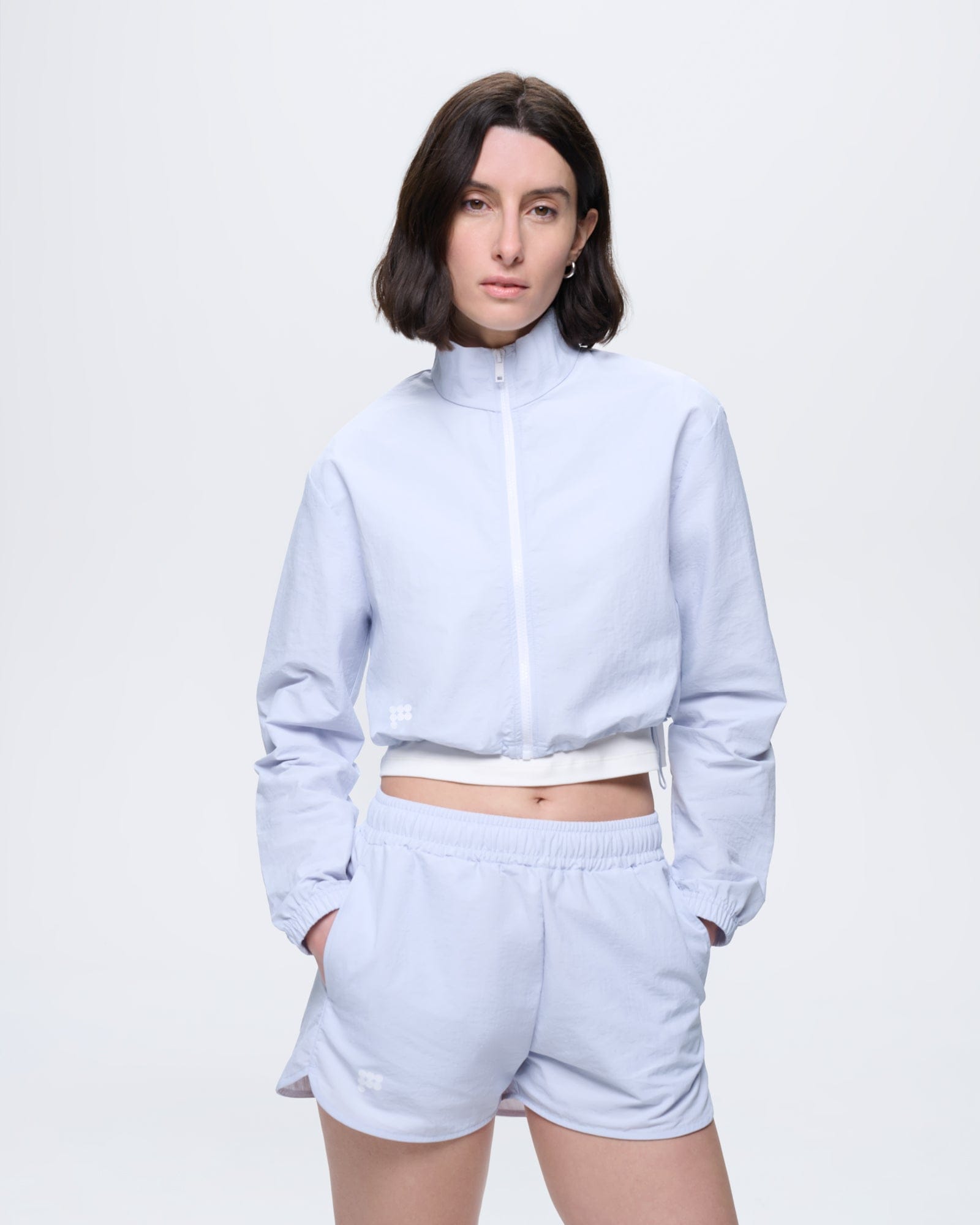 Model wears Womens Recycled Nylon Shorts Ice Grey, regular fit, with matching lightweight recycled polyamide cropped jacket