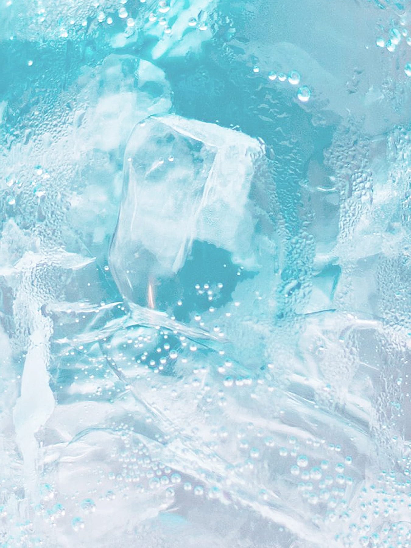 Translucent aqua blue ice cubes submerged in clear water, detailed view of sparkling effervescent bubbles and frosty surface