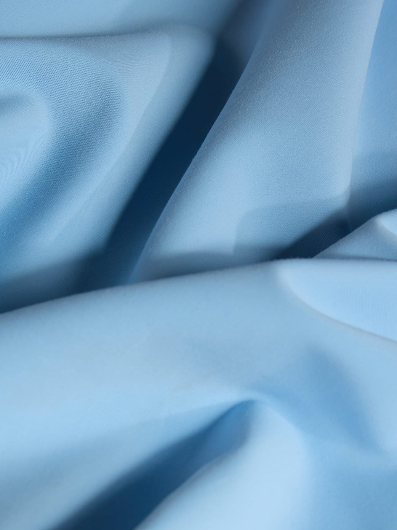 Sky blue premium knit fabric packshot. Soft, smooth textile with subtle texture, gentle drape, luxury apparel material