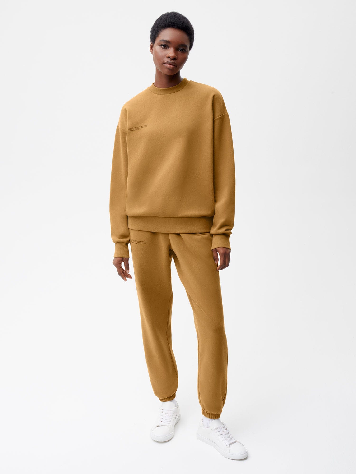 Woman in camel brown oversized cotton crewneck sweatshirt and matching relaxed fit jogger sweatpants loungewear set